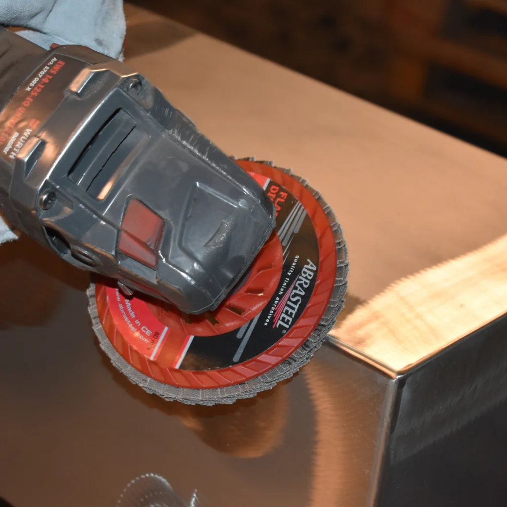 Abrasteel flap disc on an angle grinder dressing a metal surface before painting on site